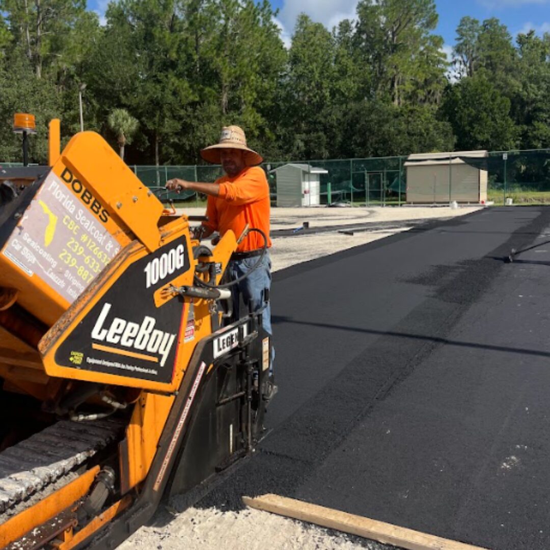 Florida Sealcoat and Striping crew laying fresh asphalt with a LeeBoy paver in Southwest Florida