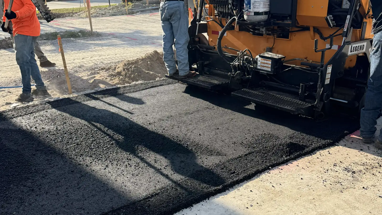 Florida Sealcoat and Striping crew laying fresh asphalt with a paver on a commercial paving job in Southwest Florida